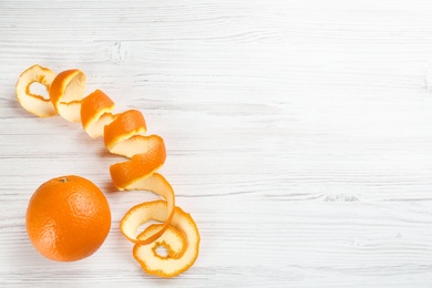 Photo of Orange fruit and peel on white wooden table, flat lay. Space for text