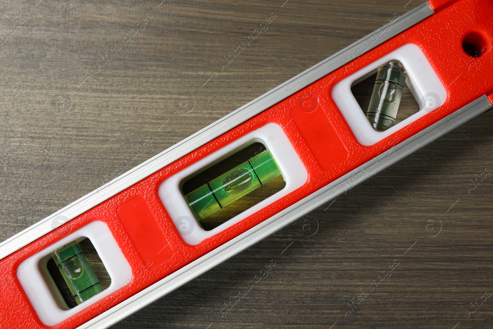 Photo of Red building level on wooden table, top view