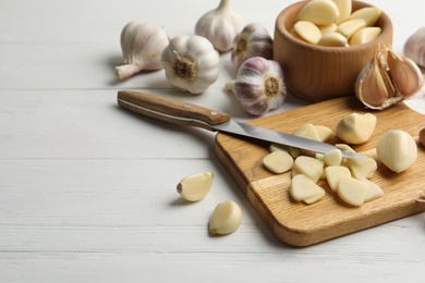 Photo of Fresh organic garlic on white wooden table. Space for text