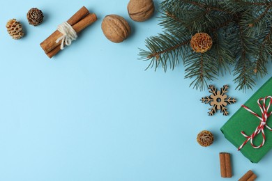 Flat lay composition with fir branch and gift box on light blue background, space for text. Winter holidays