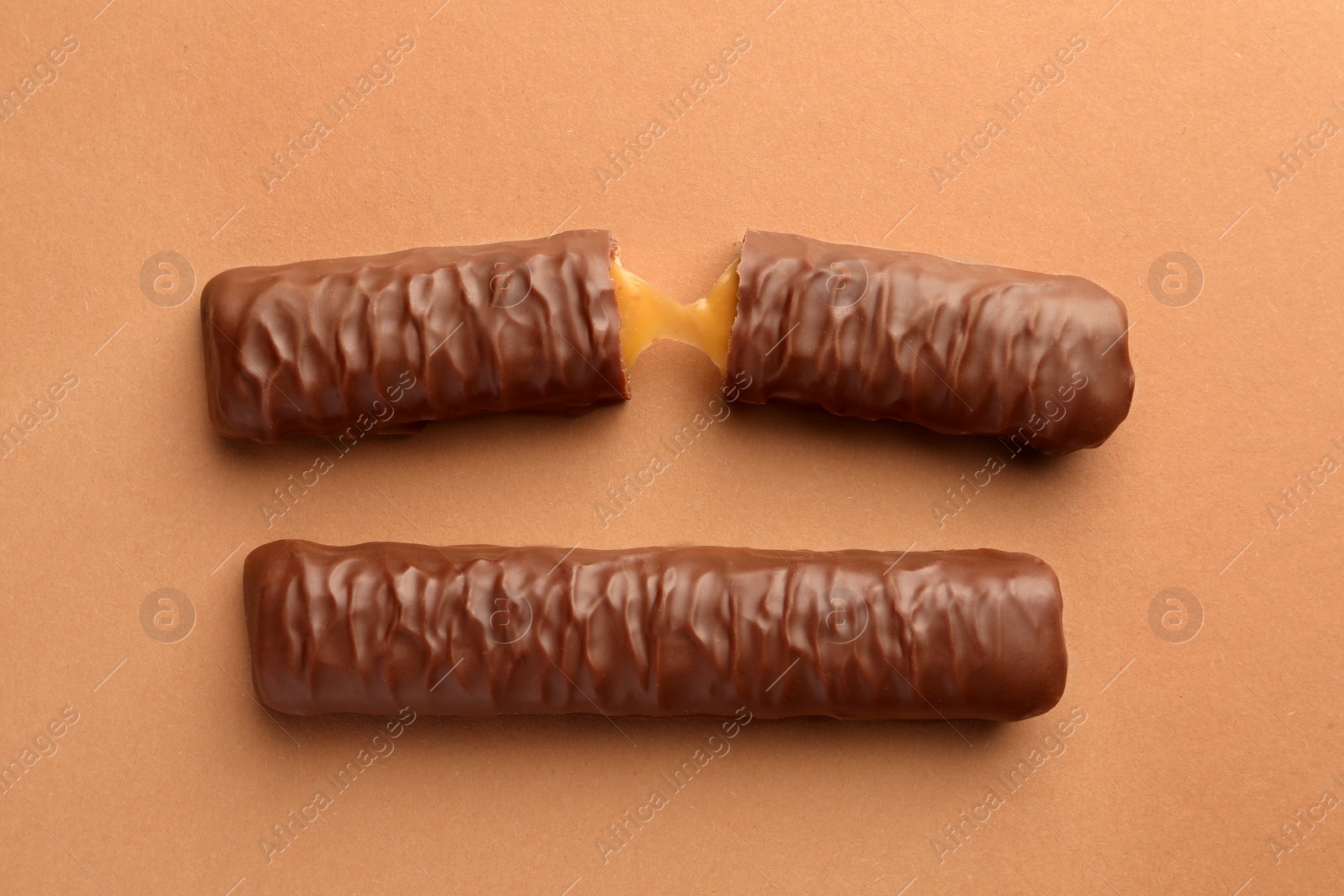 Photo of Sweet tasty chocolate bars with caramel on beige background, flat lay