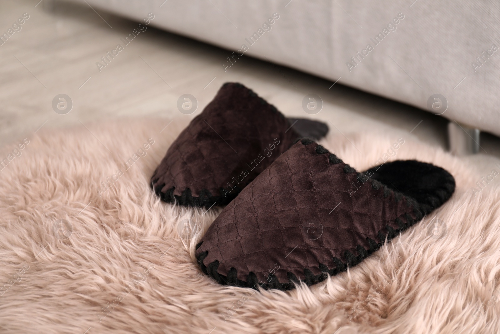 Photo of Pair of brown soft slippers on floor in room