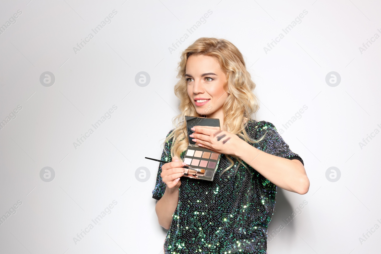 Photo of Beauty blogger with brush and eyeshadow palette on light background