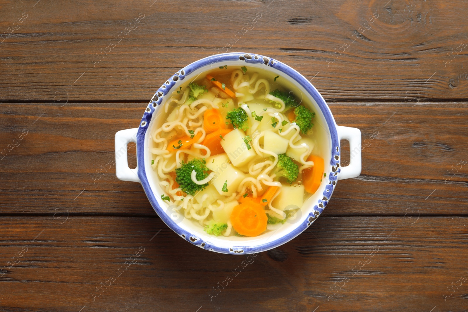 Photo of Dish of fresh homemade vegetable soup on wooden background, top view