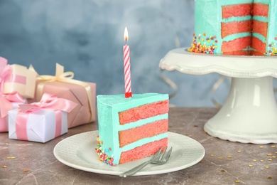 Slice of fresh delicious birthday cake with candle on table