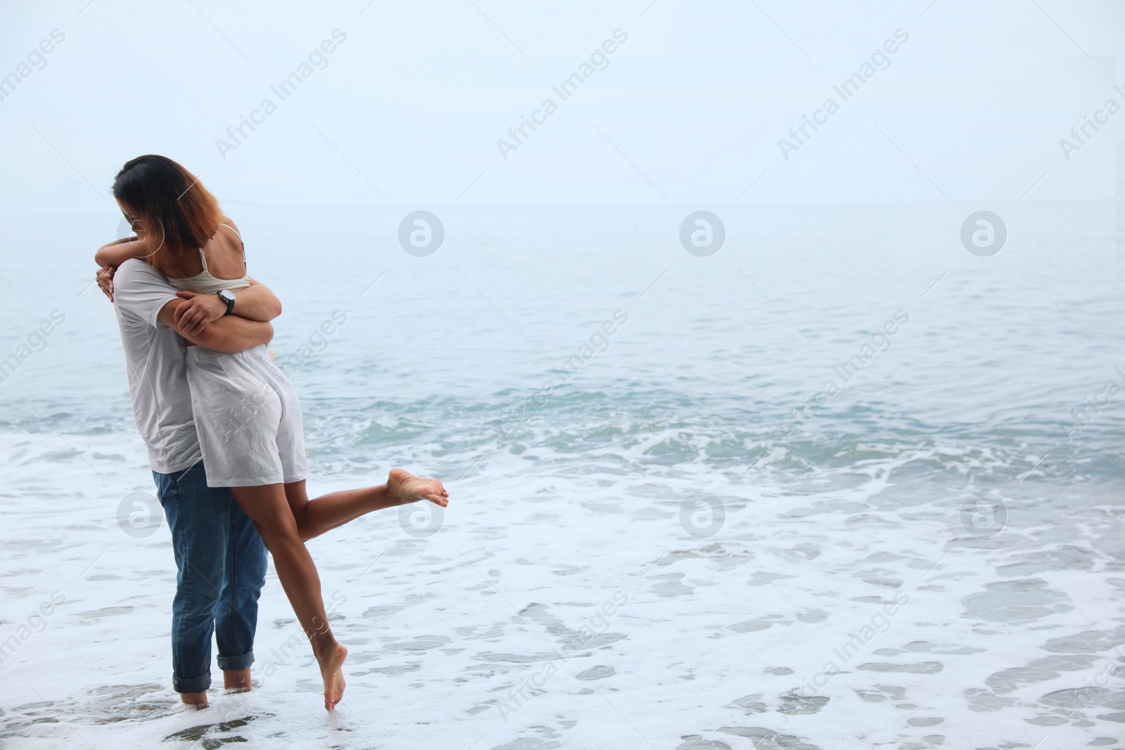 Photo of Young couple on beach near sea. Space for text