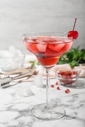 Photo of Glass of delicious cocktail with ice and cherry on white marble table