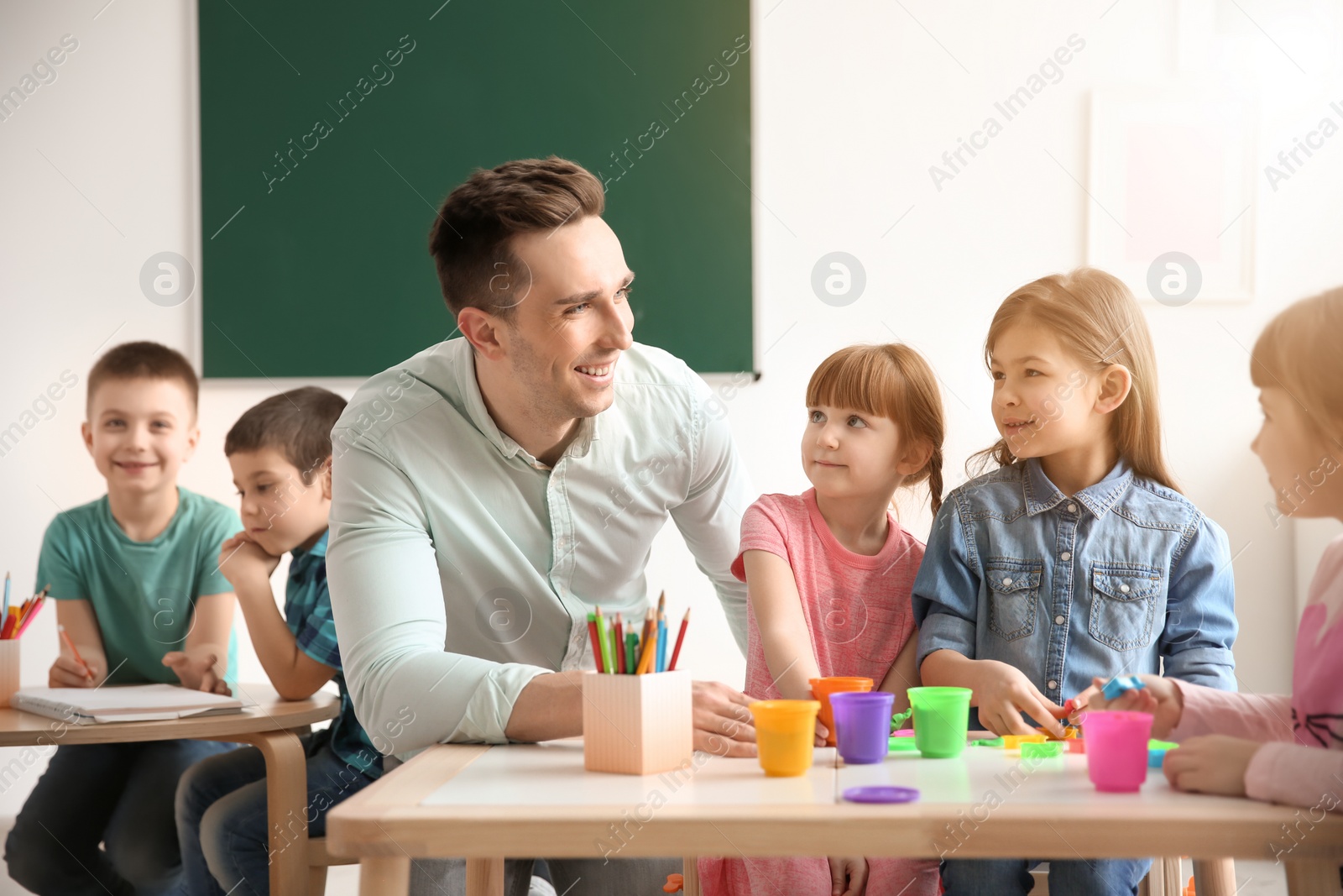 Photo of Cute little children with teacher in classroom at school