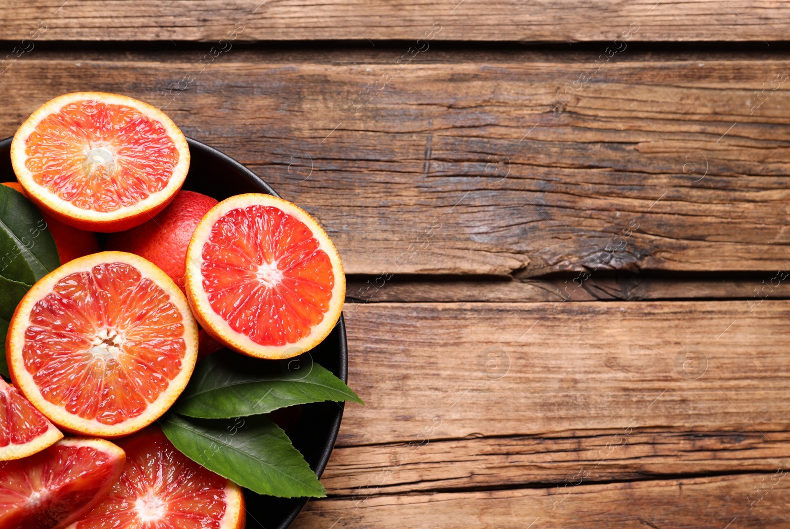 Photo of Slices of fresh ripe red orange on wooden table, top view. Space for text