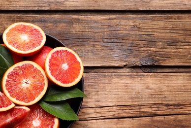 Slices of fresh ripe red orange on wooden table, top view. Space for text