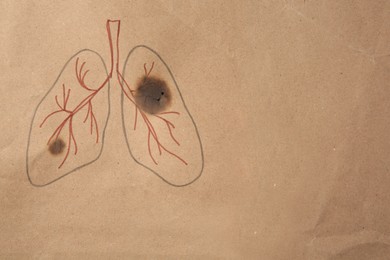 Photo of Drawn human lungs with cigarette holes on kraft paper, top view and space for text. No smoking concept