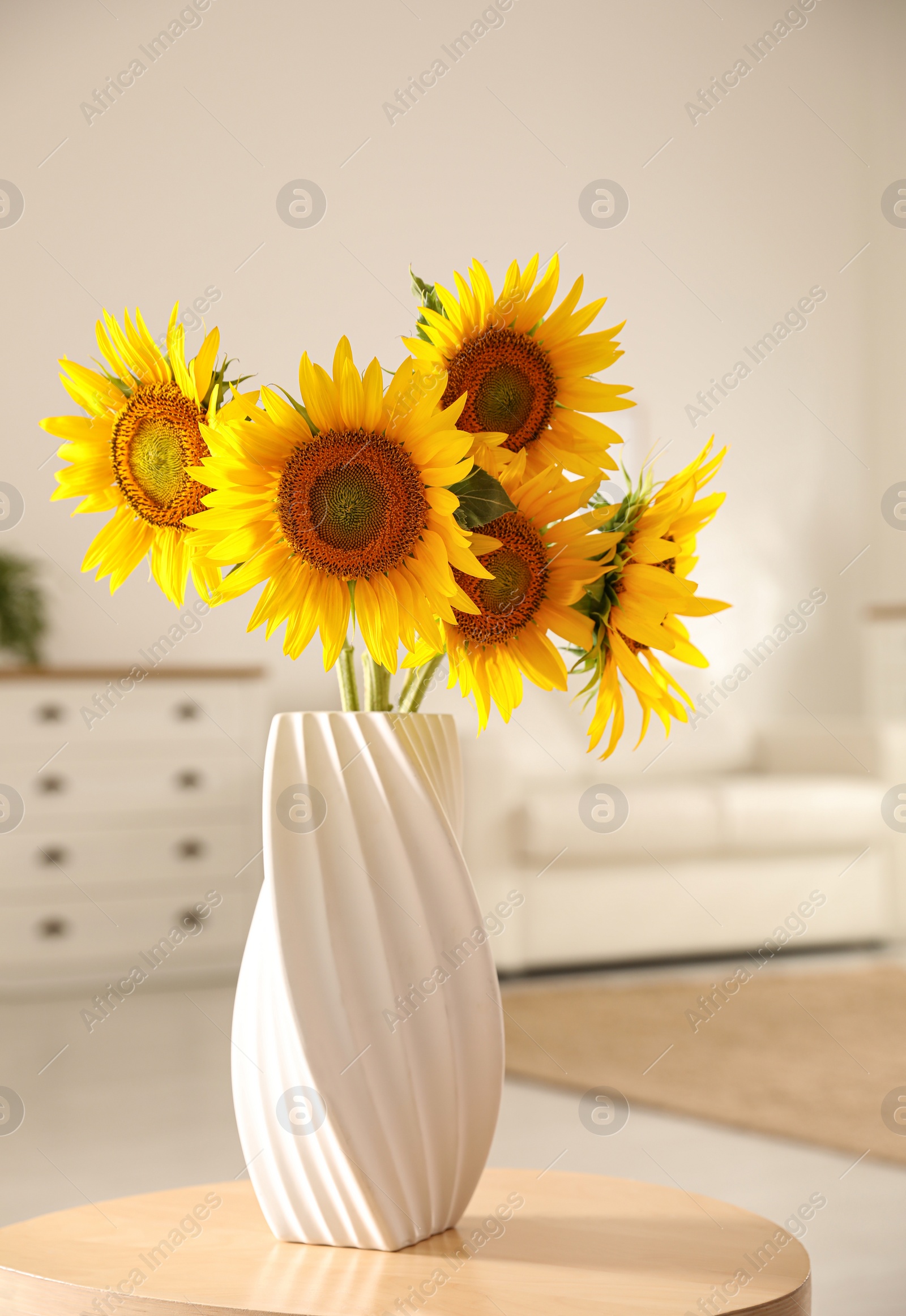 Photo of Bouquet of beautiful sunflowers in vase on table indoors