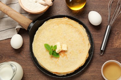 Delicious crepes and ingredients on wooden table, flat lay