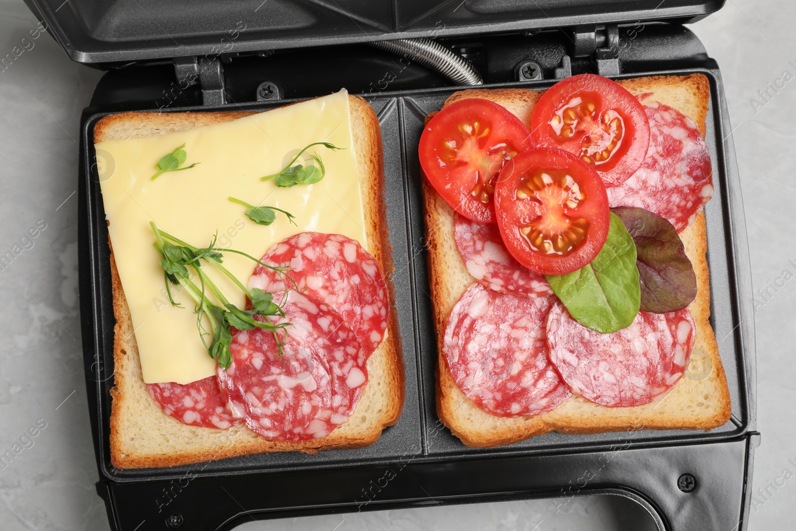 Photo of Modern grill maker with sandwiches on light grey table, top view