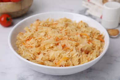 Photo of Bowl with tasty sauerkraut on white marble table, closeup