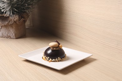 Delicious chocolate dessert decorated with nuts and macaron on wooden table