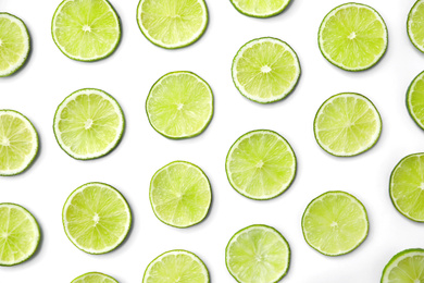 Photo of Slices of fresh juicy limes on white background, flat lay