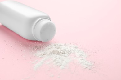 Photo of Bottle and scattered dusting powder on pink background, closeup. Baby cosmetic product
