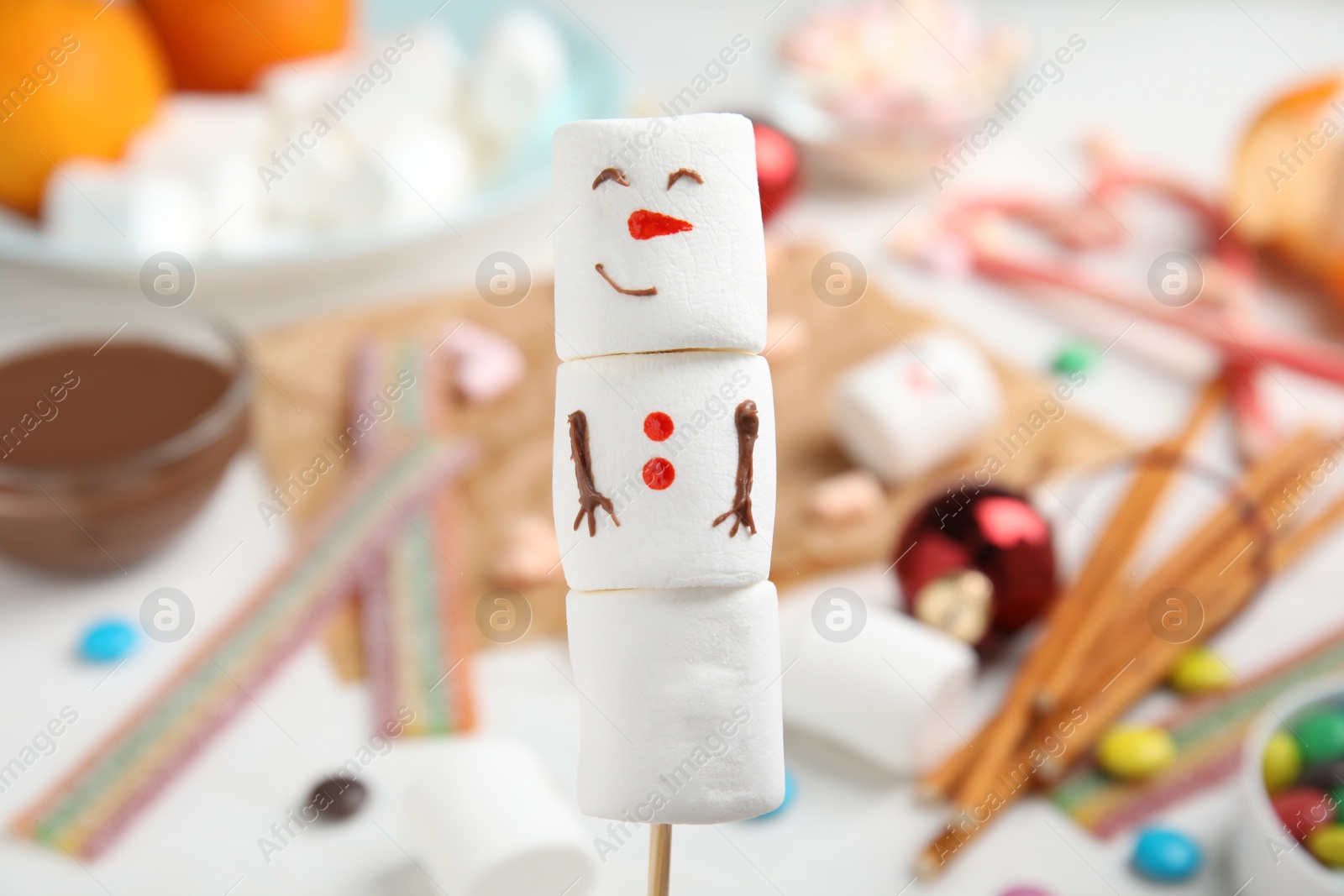 Photo of Funny snowman made of marshmallows on blurred background, closeup
