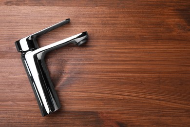 Photo of Single handle water tap on wooden table, top view. Space for text