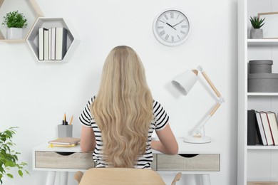 Home workplace. Woman working at comfortable desk in room, back view