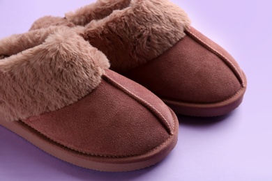 Pair of stylish soft slippers on violet background, closeup