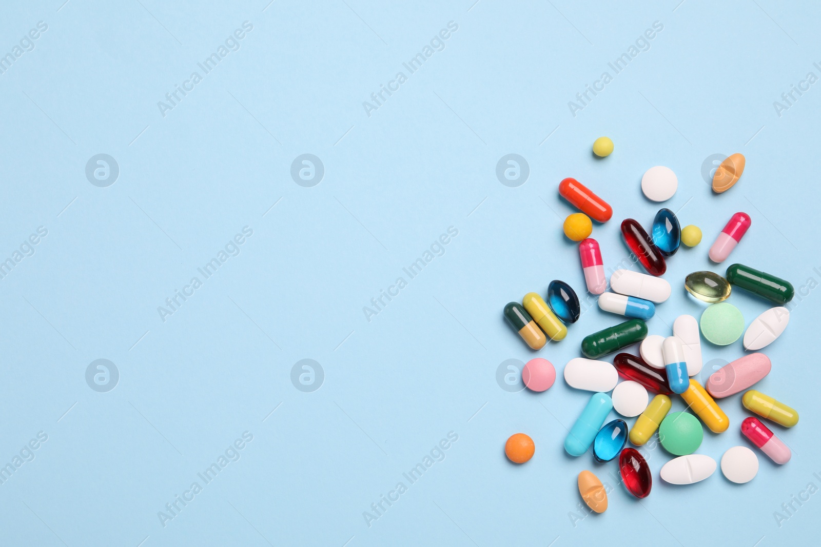 Photo of Many different pills on light blue background, flat lay. Space for text