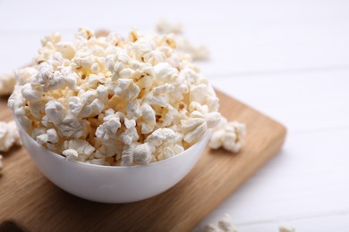 Photo of Tasty popcorn on white wooden table, closeup
