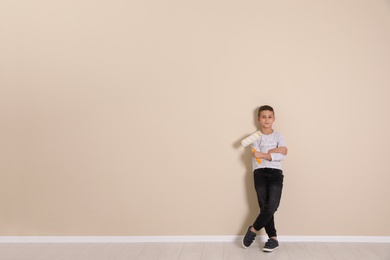 Photo of Child with roller brush near color wall. Space for text