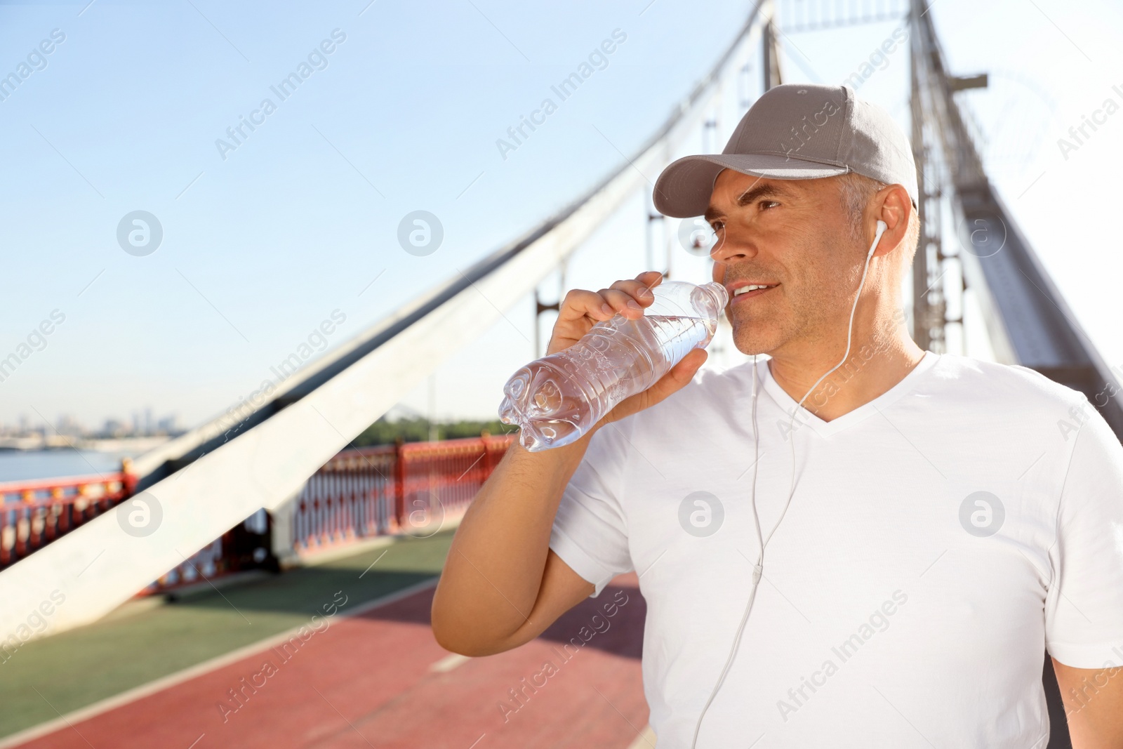 Photo of Handsome mature man enjoying music in headphones on bridge, space for text. Healthy lifestyle