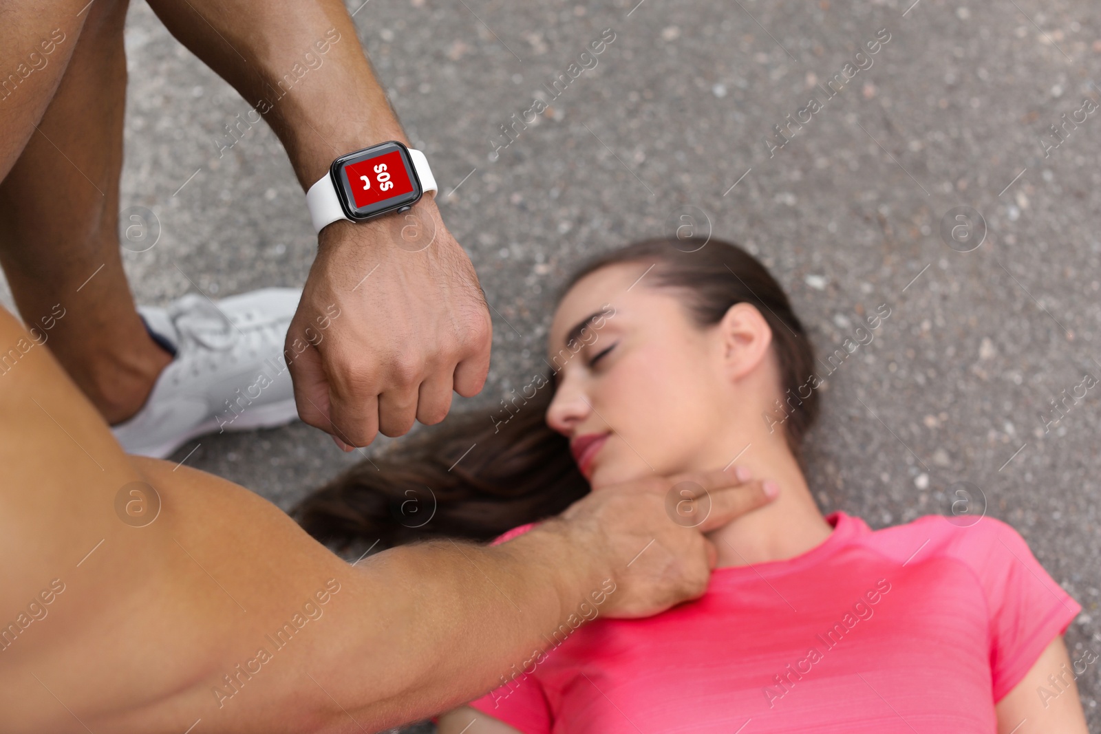 Image of SOS function. Man sending emergency call via smartwatch while checking woman's pulse outdoors, closeup