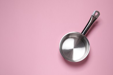 Empty steel saucepan on pink background, top view. Space for text