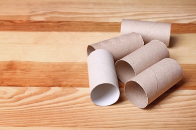 Photo of Empty toilet paper rolls and space for text on wooden background