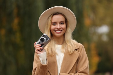 Autumn vibes. Portrait of happy woman with camera outdoors