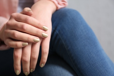 Photo of Woman with gold manicure on grey background, closeup. Nail polish trends