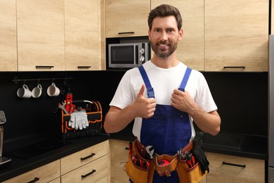 Photo of Professional plumber with tool belt in kitchen