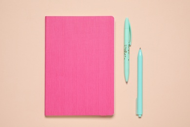 Photo of Stylish notepad and pens on beige background, flat lay