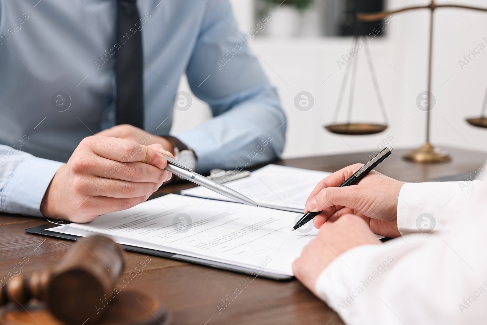 Photo of Lawyers working with documents at wooden table in office, closeup