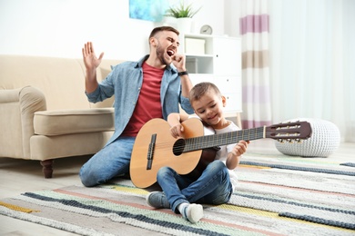 Father and son playing guitar and singing at home