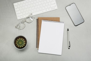 Photo of Flat lay composition with notebooks, smartphone, glasses and pen on light grey table