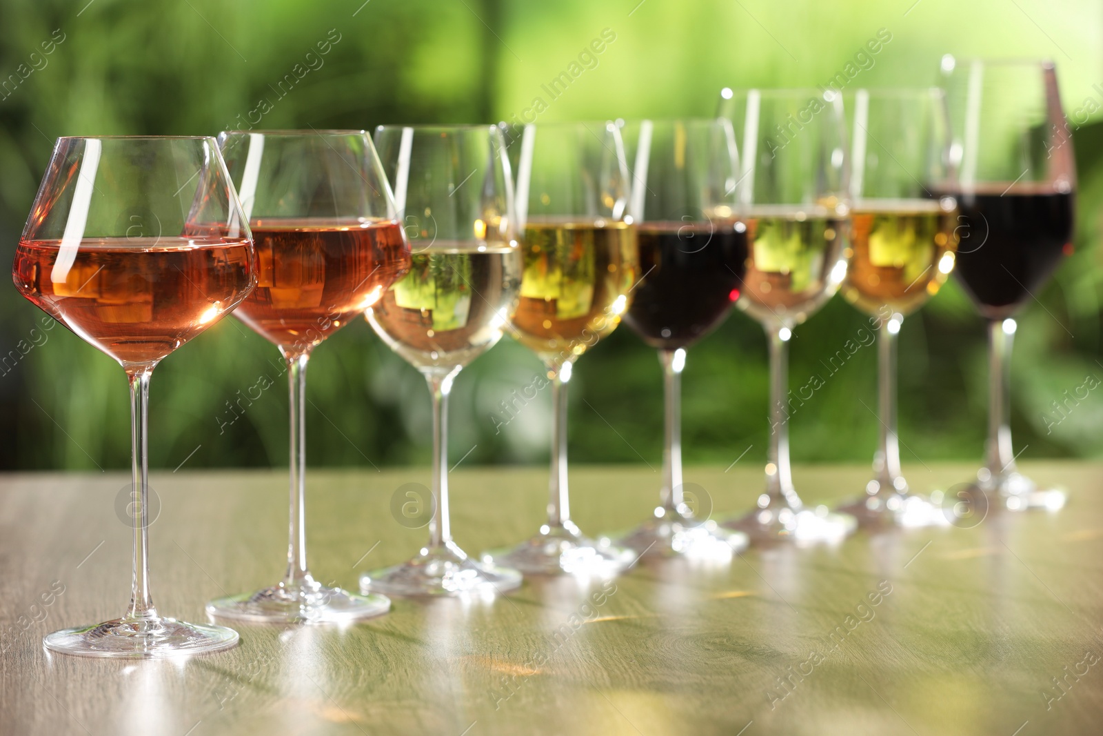 Photo of Different tasty wines in glasses on wooden table