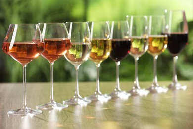 Different tasty wines in glasses on wooden table