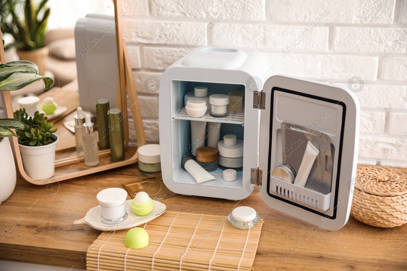 Photo of Mini fridge with cosmetic products on wooden vanity table