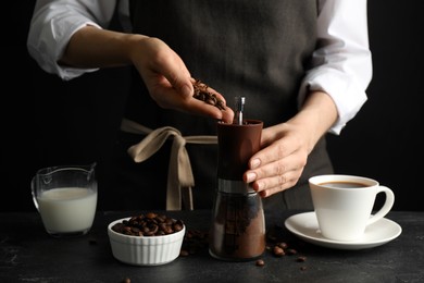 Photo of Woman using manual coffee grinder at black table, closeup