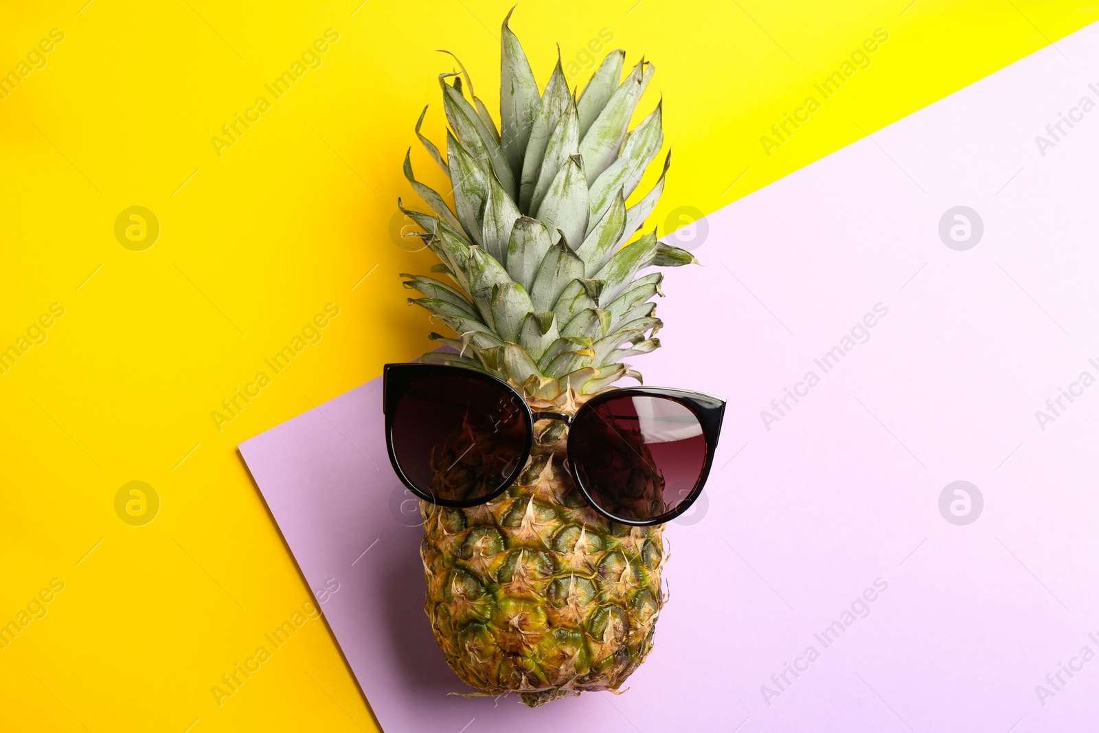 Photo of Pineapple with stylish sunglasses on color background, top view