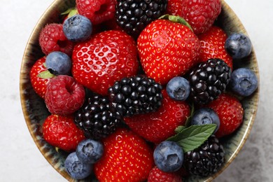 Photo of Different fresh ripe berries in bowl on table, top view