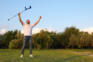 Photo of Man raising elbow crutch up to sky on sunny day, space for text. Healing miracle