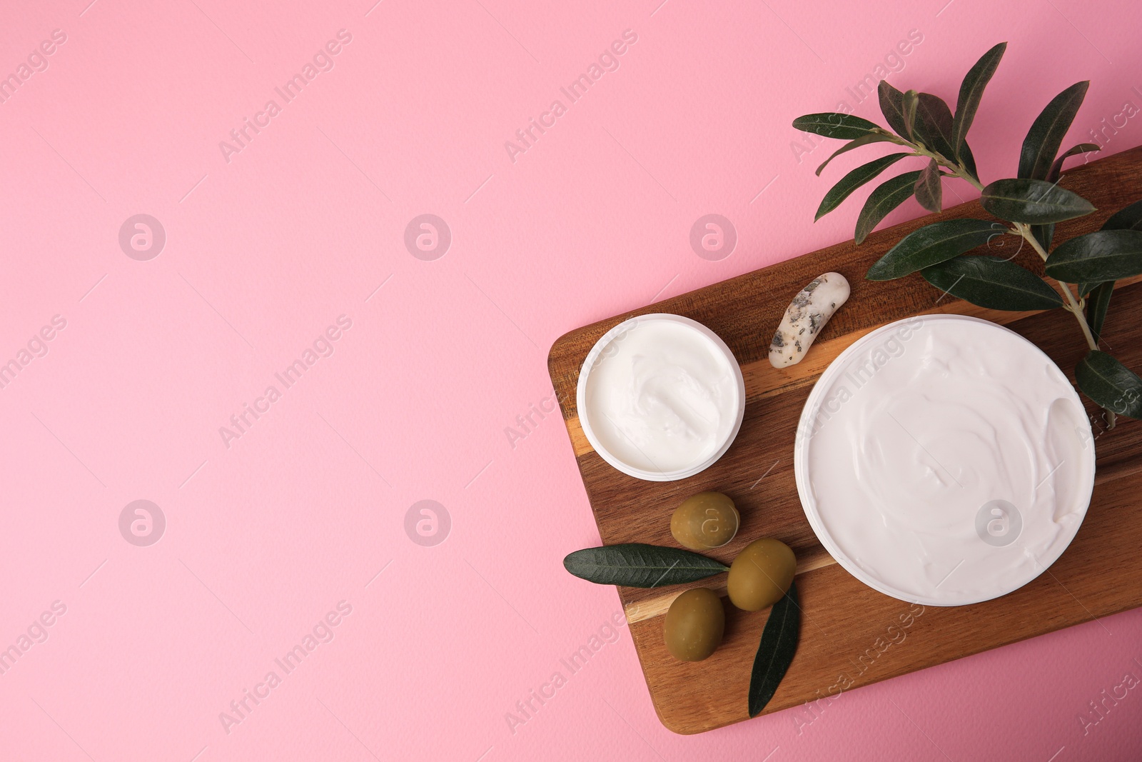 Photo of Natural cosmetic. Olive creams, mineral and ingredient on pink background, top view. Space for text