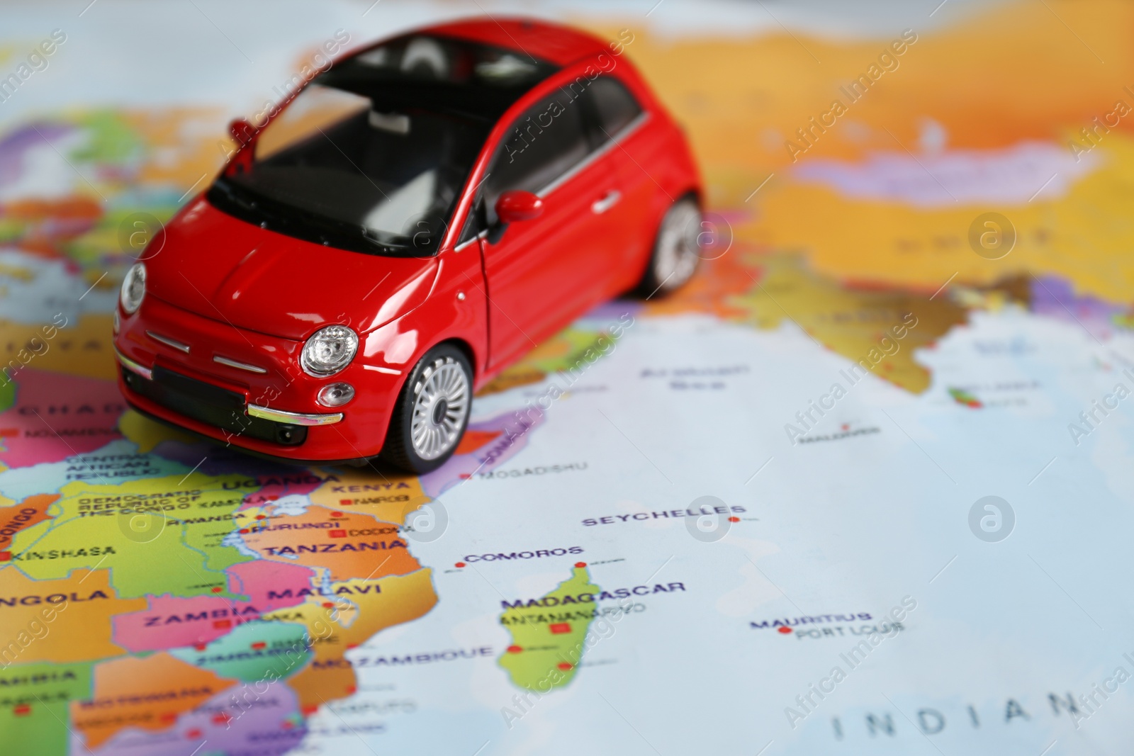 Photo of Red toy car on world map, closeup. Trip planning