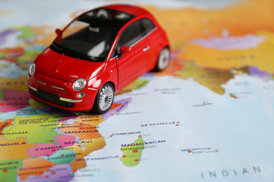 Red toy car on world map, closeup. Trip planning